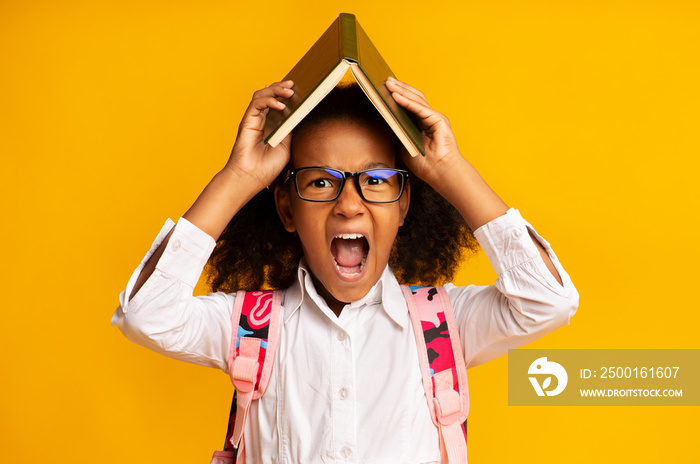 Naughty African Schoolgirl Screaming Holding Book On Head, Yellow Background