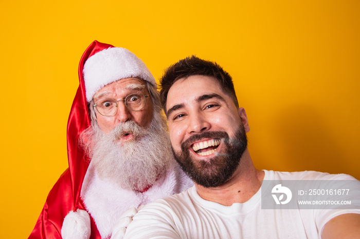 Young boy making a selfie with real Santa Claus on yellow background. Closeup of selfie with Santa Claus.