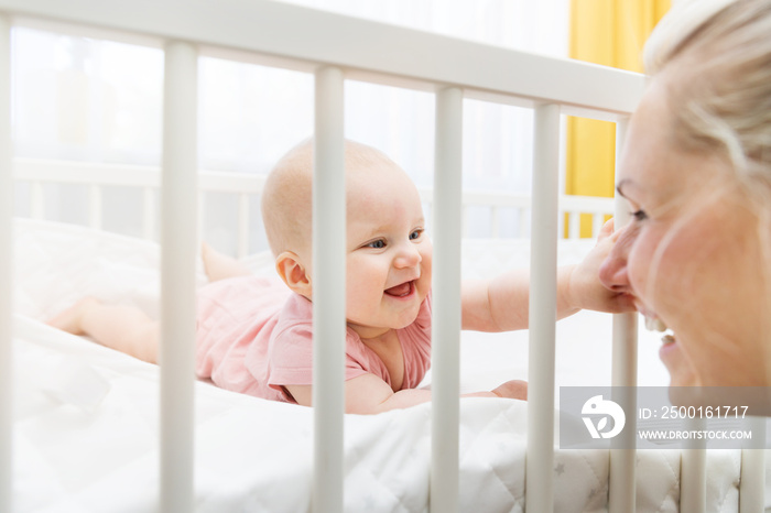 mother playing with her baby in crib and having fun together