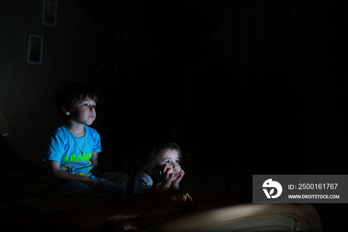 Small children in a dark room watching TV