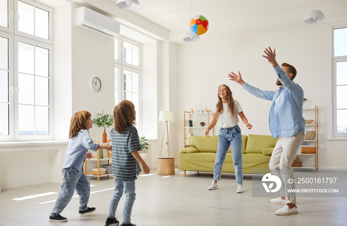 Smiling young Caucasian family with small children relax playing with ball in living room. Happy parents mom and dad have fun relax involved in game activity with kids at home. Active weekend.