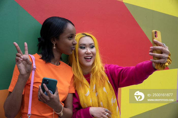 Young female friends using taking selfie outdoors