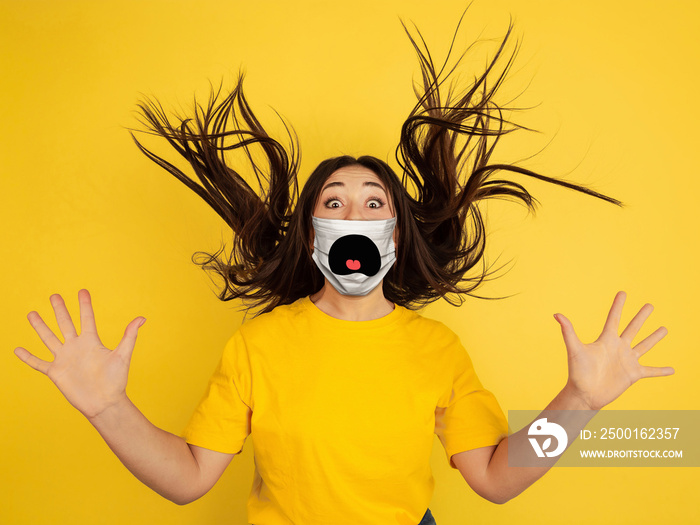 Crazy shocked. Portrait of young caucasian woman with emotion on her protective face mask isolated on studio background. Beautiful female model. Human emotions, facial expression, sales, ad concept.