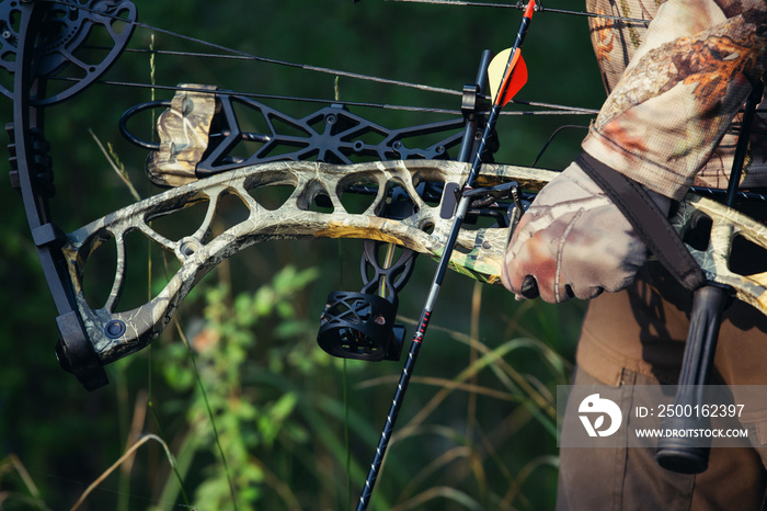 Hunter in the woods with bow and arrow ready to take aim at his prey