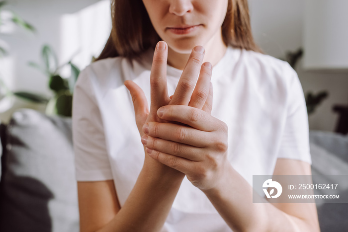 Sad girl massage hand with wrist pain, rheumatoid arthritis concept. Close up of young woman suffer from numbing pain in hand, numbness fingertip, arthritis inflammation, peripheral neuropathies