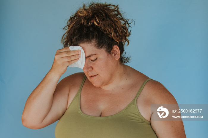 closeup protrait of a plus size woman wiping forehead