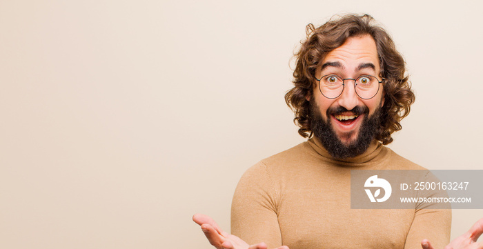 young bearded crazy man feeling happy, astonished, lucky and surprised, like saying omg seriously? Unbelievable against flat color wall