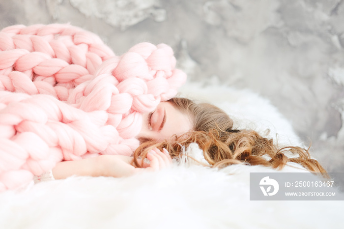 Young woman sleeping under warm peach color throw blanket