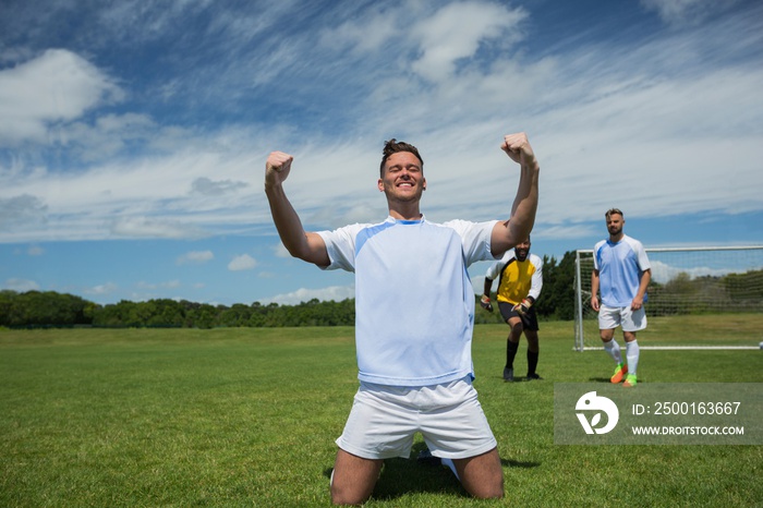 Excited football player in celebrating scoring goal kneeling on