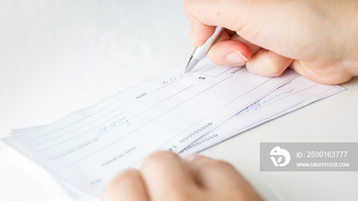 Man filling banking cheques for monthly payments and taxes