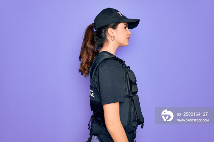 Young police woman wearing security bulletproof vest uniform over purple background looking to side, relax profile pose with natural face and confident smile.
