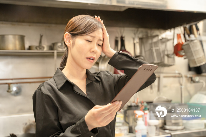 飲食店で伝票確認し困る女性スタッフ