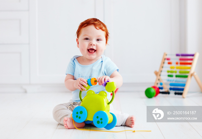 happy infant baby boy playing with toys at home