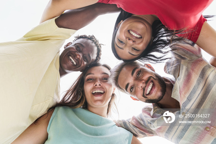 Group of young friends standing in circle and smiling to camera - Happy diverse students having fun hugging together