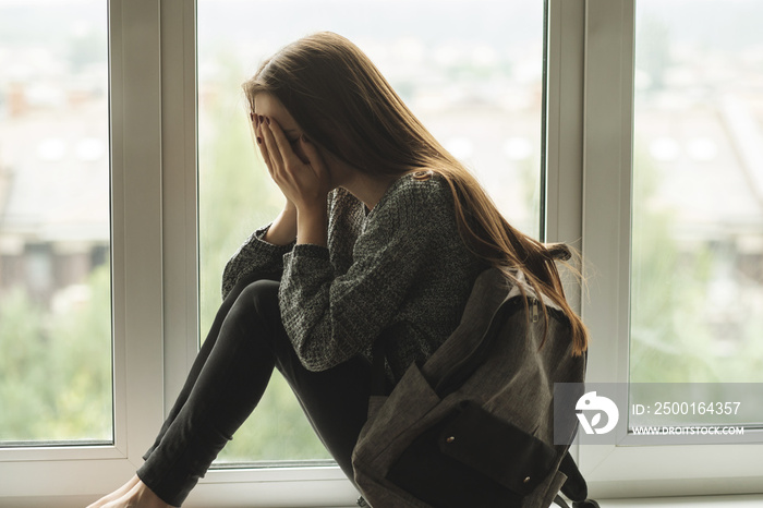 bullying teenager school,teen girl is crying on the window,harassment and teasing, abuse of peers