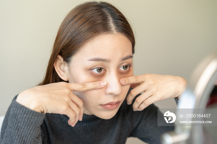 Bored, insomnia asian young woman, girl looking at camera, hand touching under eyes with problem of black circles or panda puffy, swollen and wrinkle on face. Sleepless, sleepy healthcare person.