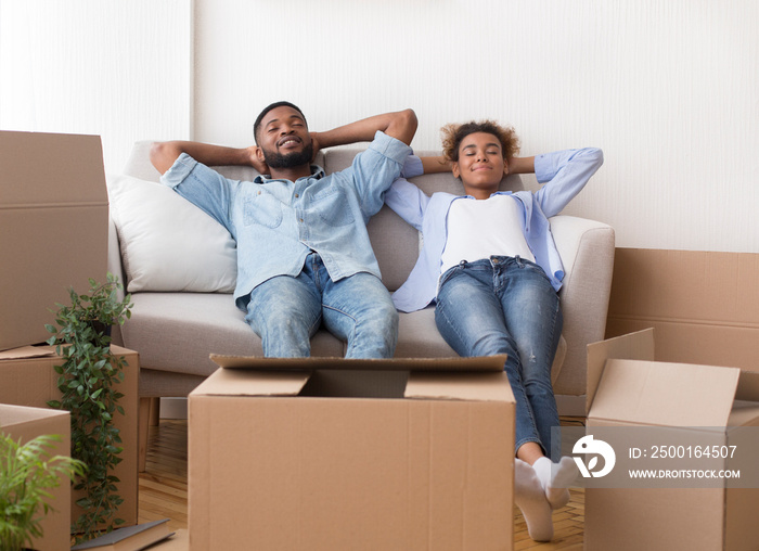 African American Spouses Relaxing Sitting On Couch In New Apartment