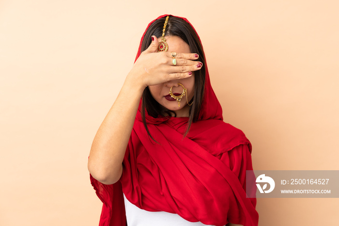 Young Indian woman isolated on beige background covering eyes by hands. Do not want to see something