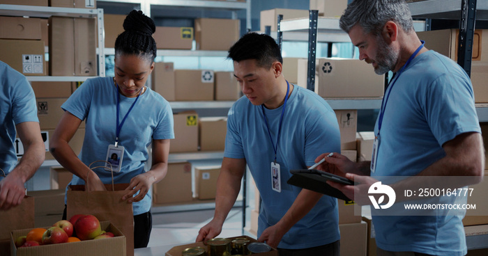 Charity Help Center. Aid Organisation. Multi-ethnic Young Volunteer Team Cooperating in Free Food Delivery Preparation Coworking at Warehouse.