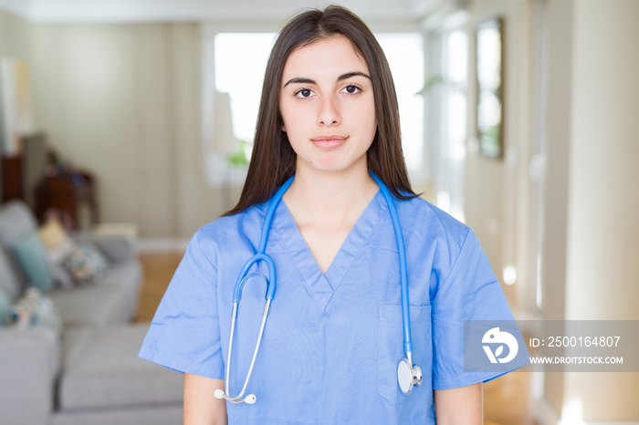 Beautiful young nurse woman wearing uniform and stethoscope at the clinic with serious expression on face. Simple and natural looking at the camera.