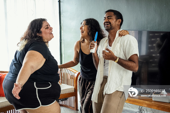 Friends dancing and singing together at home on a weekend