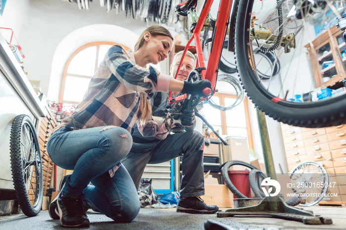 In a bike repair workshop with two bicycle mechanics