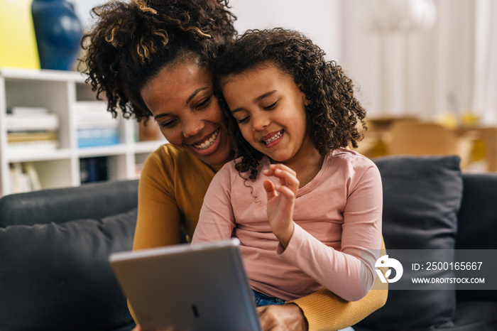 Mixed race mother and daughter are using tablet together at home, fun time