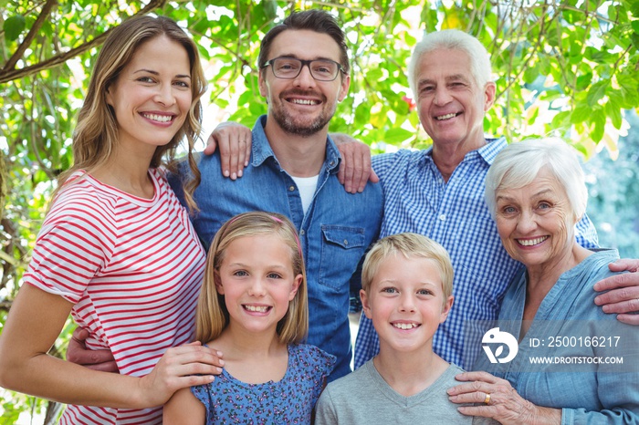 Smiling family standing against tree