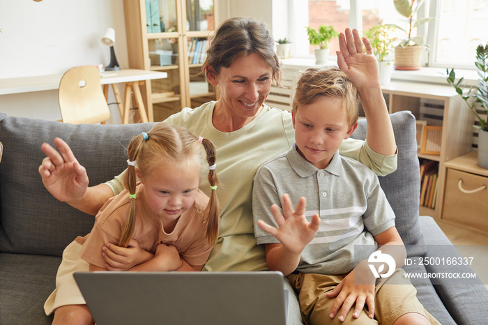 Portrait of happy family with special needs child waving at camera while enjoying video chat with relatives