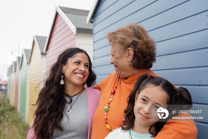 Portrait of grandmother, mother and granddaughter by beach hut