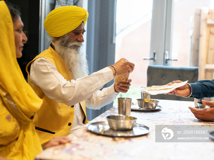 Family in traditional clothing eating meal at home