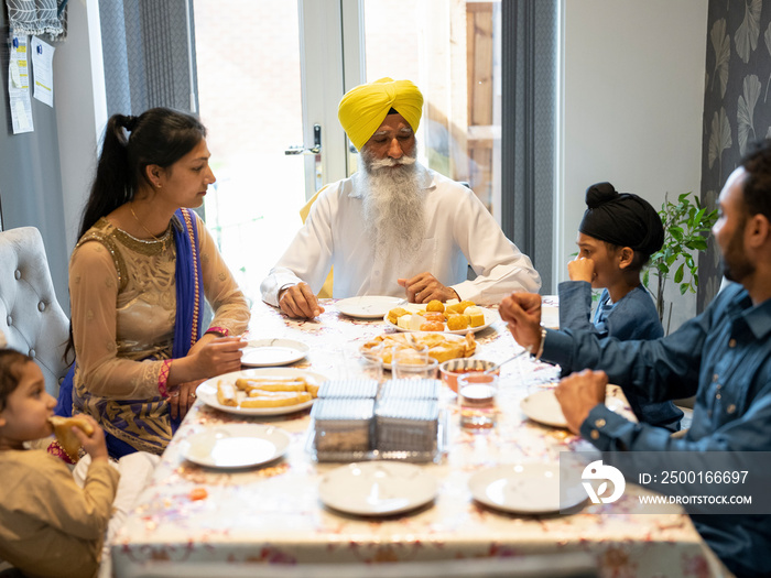 Three-generation family (2-3,6-7) having traditional meal at home