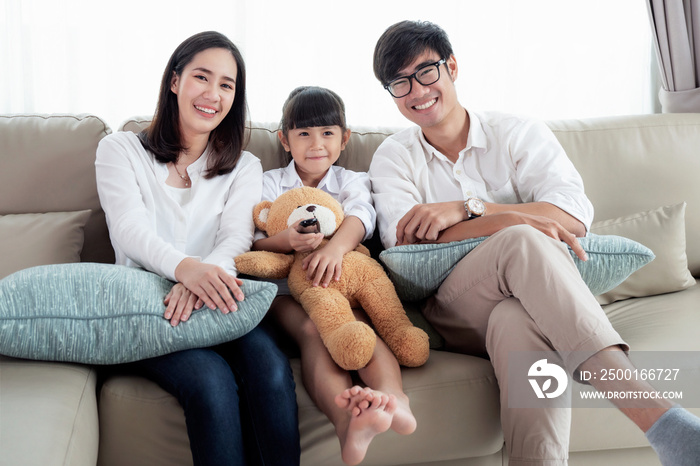 Asian family watching TV and sit on sofa in leving room