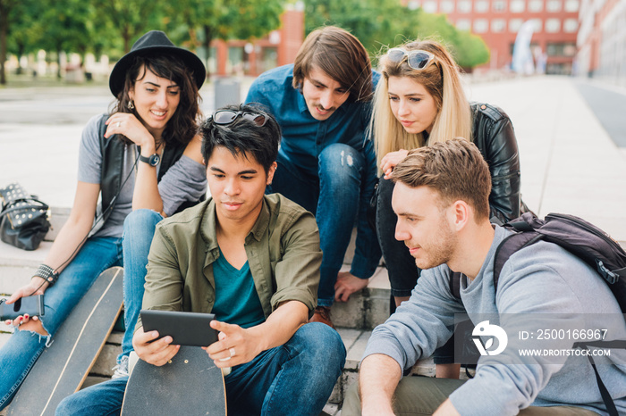 Group of young friends watching smartphone while sitting outdoors