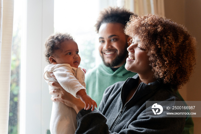 Smiling parents looking at baby daughter at home