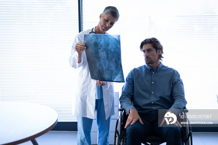 Mature female doctor showing x-ray report to patient in clinic