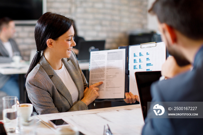 Two young businesswoman interacting at meeting in office