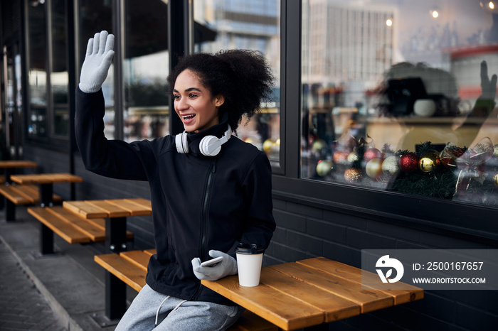 Person waving to her friend from a cafe table