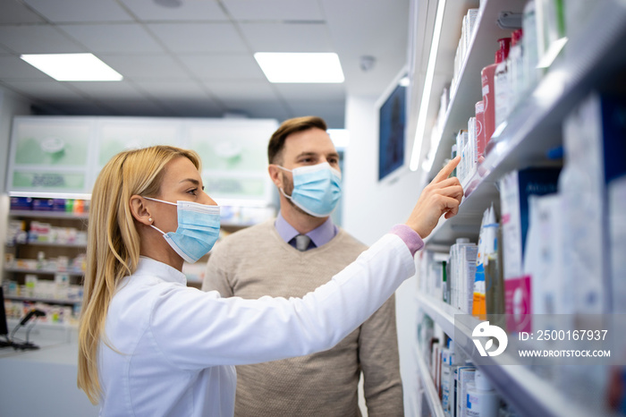 Female pharmacist selling new products to the customer in pharmacy shop.