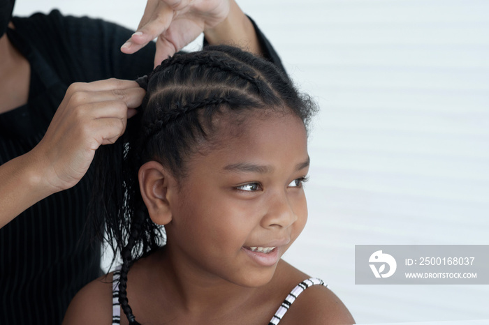 Close up of expert female hands making braids on little girl head, making Afro braids hairstyle