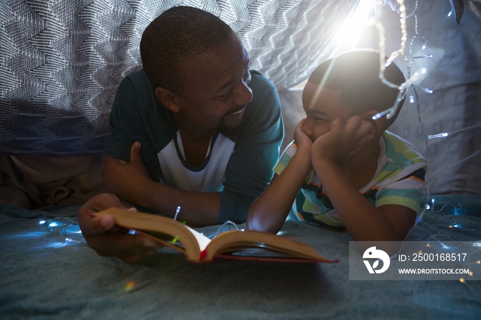 Father and son reading book in bedroom