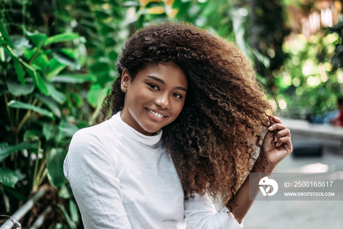 Happy smiling woman touching her curly hair.