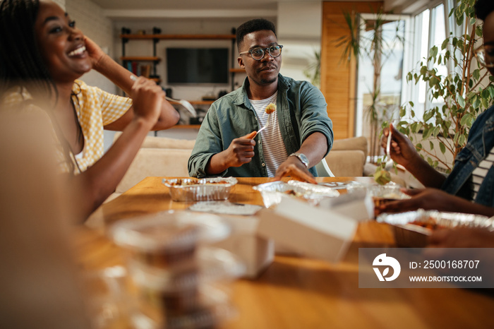 Four black friends having take out food at home together