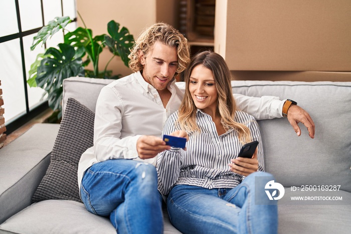 Man and woman couple using smartphone and credit card at new home