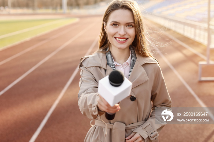 Beautiful reporter with microphone at the stadium