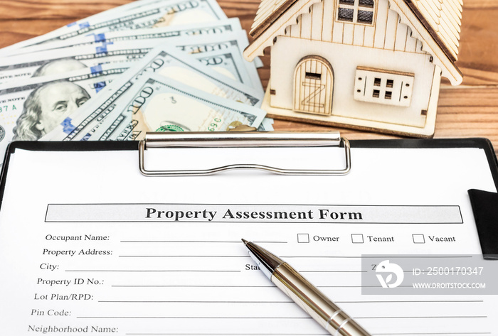 Property assessment form on clipboard over table with model of house and money.