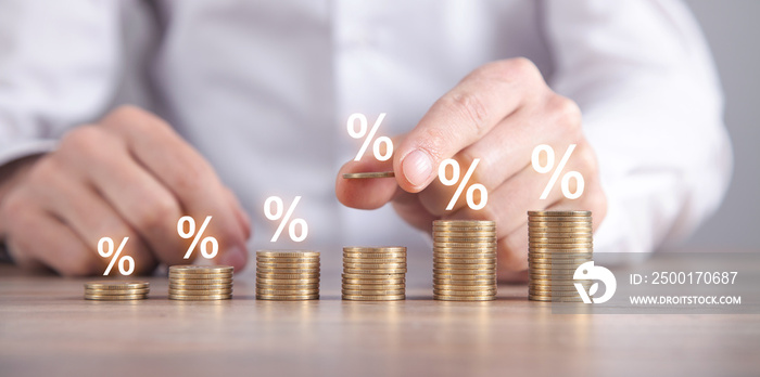 Man stacking coins with a percent symbols.