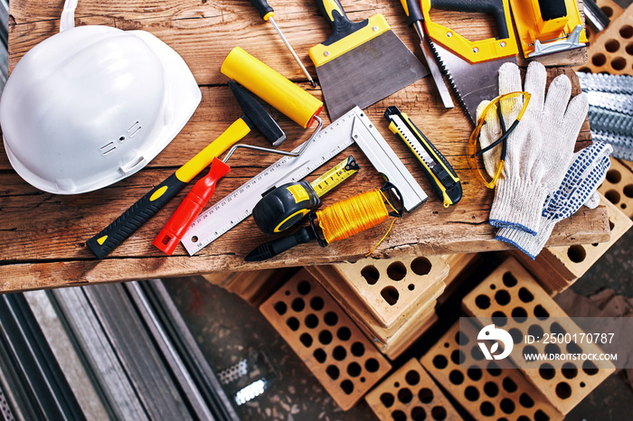 Home repairs. Construction tools, bricks and helmet top view