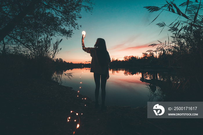 Ragazza immagina il futuro di fronte a un lago al tramonto