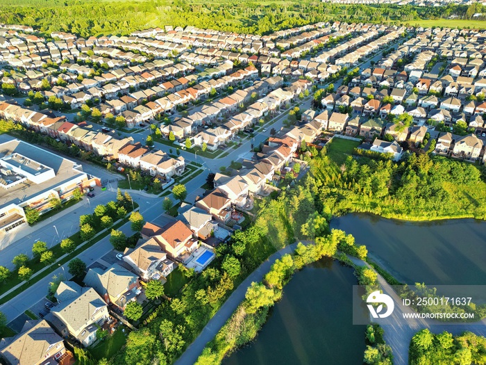 Drone aerial view of traditional North America residential houses and streets near park pond.